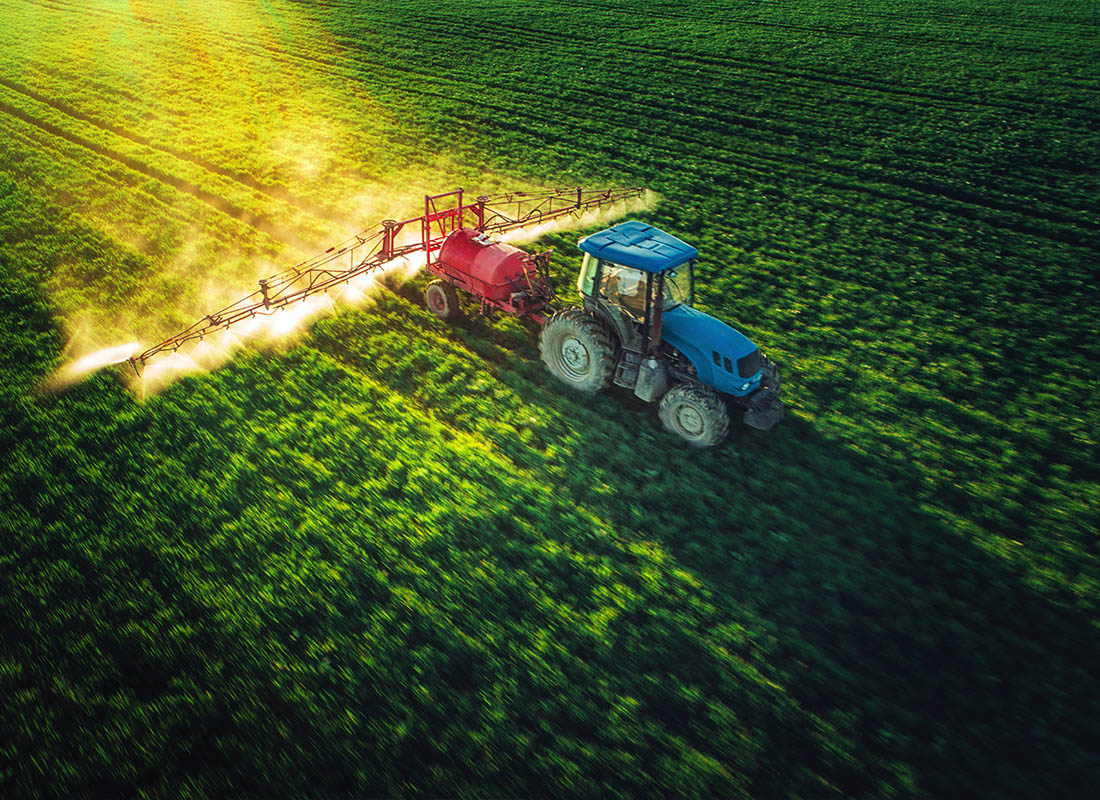Insurance by Industry - Aerial View of Farming Tractor Plowing and Spraying on Field